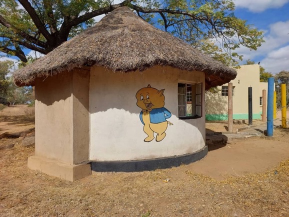 The thatched childcare hut for babies and toddlers, painted with a cartoon bear.